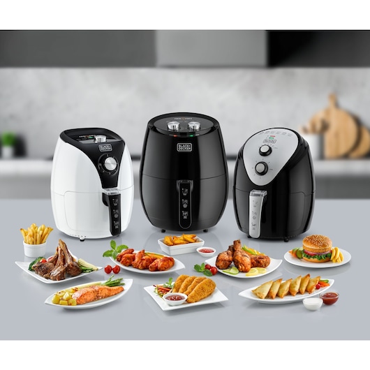 Photo of three BLACK+DECKER AF220 air fryers on a kitchen counter, surrounded by various plated foods.