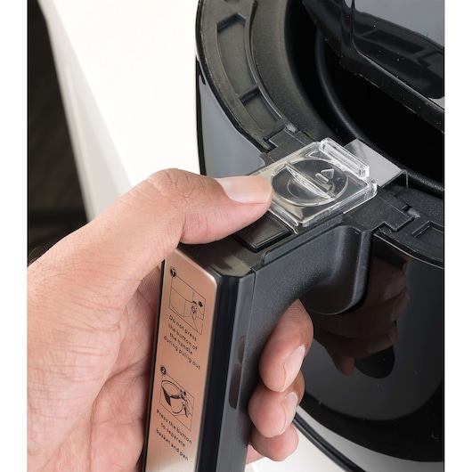 BLACKDECKER air fryer AF300 close-up of handle with instructions label and thumb pressing release button.