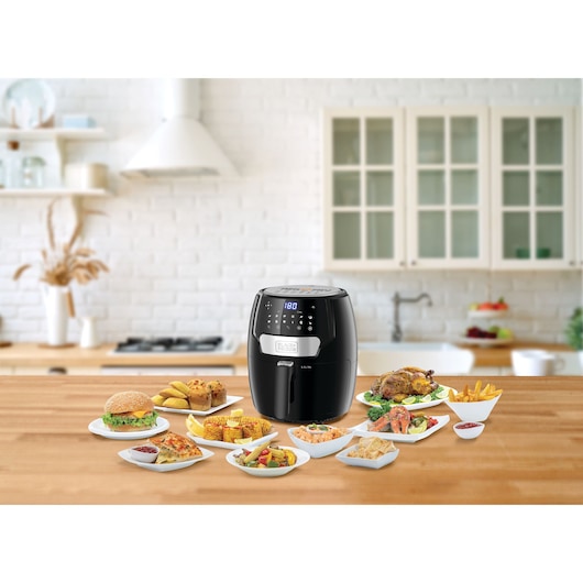 BLACKDECKER AF4037 air fryer with digital display on kitchen counter, surrounded by plates of assorted food.