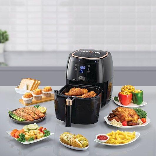 Photo of BLACKDECKER AF5539 air fryer with digital display, surrounded by cooked food dishes on a kitchen counter.