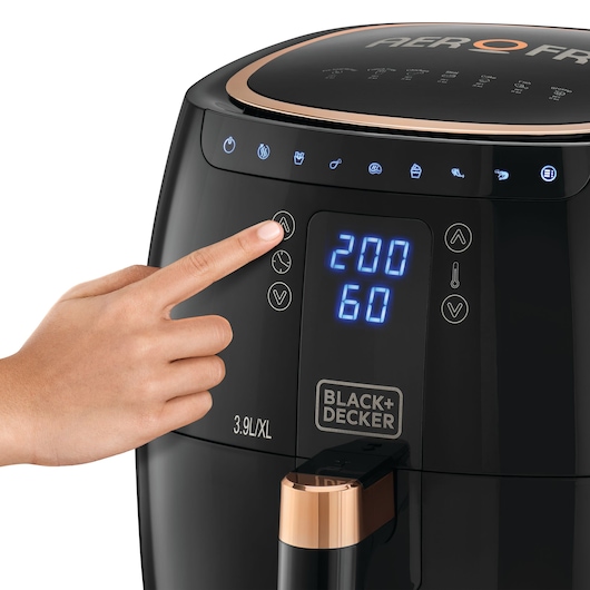 Photo of BLACK+DECKER AF5539 air fryer with illuminated digital controls, hand adjusting temperature, close-up.