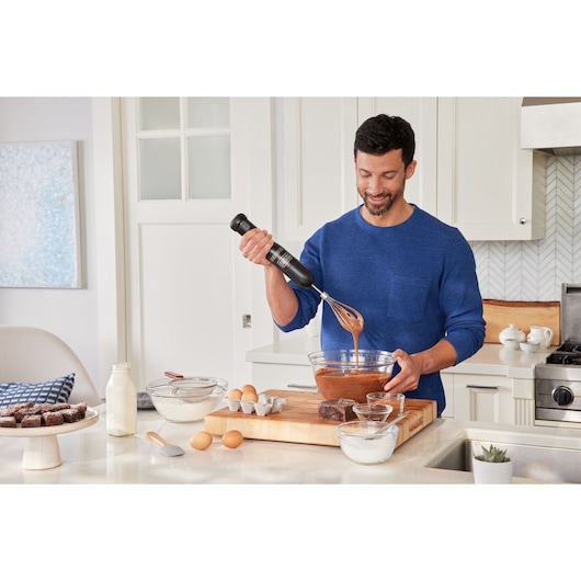 BLACKDECKER BCKM1016KSB hand mixer used to mix batter in a glass bowl on a kitchen counter.