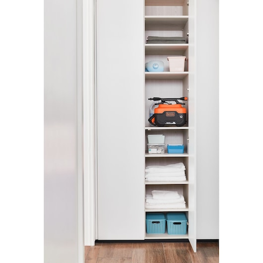 Photo of BLACKDECKER BEPW1300H pressure washer stored on a shelf in a white closet with various household items.
