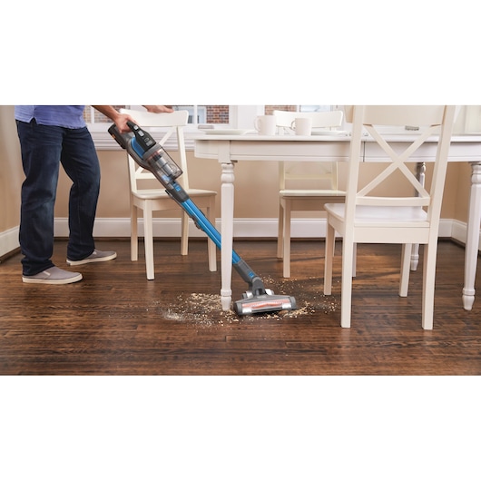 BLACKDECKER BHFEV362D cordless stick vacuum cleaning debris on hardwood floor in kitchen.