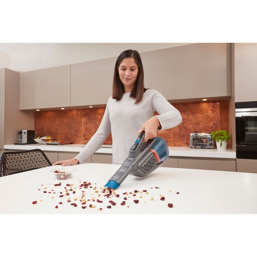 BLACKDECKER BHHV320B handheld vacuum cleaning crumbs from a kitchen countertop.