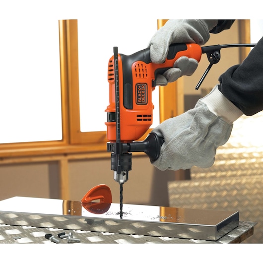 Photo of BLACKDECKER CD714REK orange and black drill in use on a metal surface by gloved hands.