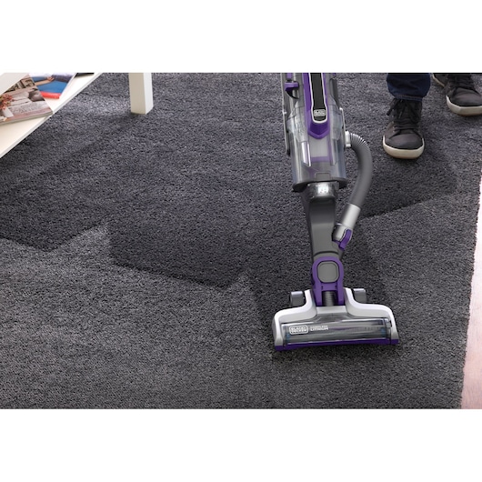 Photo of BLACKDECKER CUA525BHP vacuum cleaner in use on dark carpet, showing cleaning efficiency.