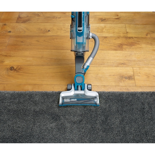 BLACKDECKER CUA525BH upright vacuum on grey carpet and wooden floor, top angle.