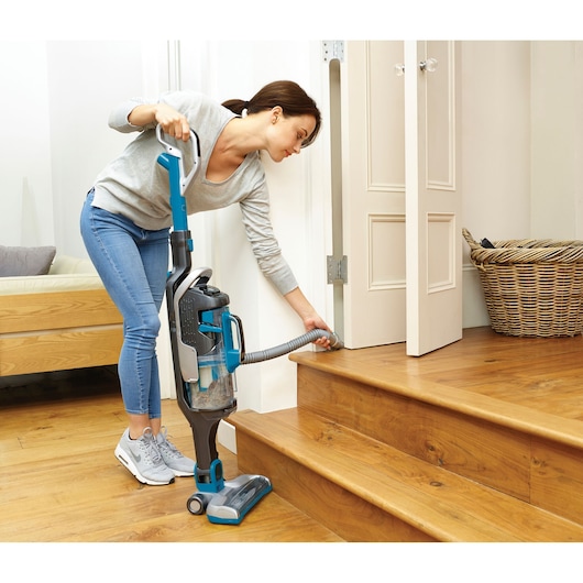 BLACKDECKER CUA525BH upright vacuum cleaner with blue accents, used to clean wooden stairs.