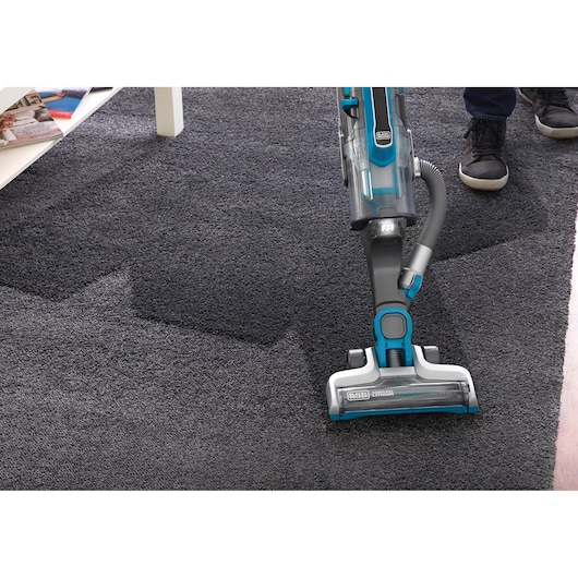 BLACKDECKER CUA525BH upright vacuum cleaner cleaning dark carpet, angled top view.