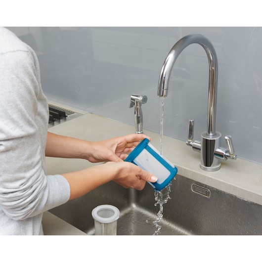 BLACKDECKER CUA525BH vacuum filter being rinsed under sink faucet, product cleaning demonstration.