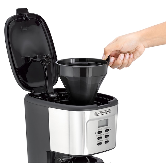 A BLACK+DECKER coffee maker with its lid open, showing a hand placing or removing the black filter basket from inside the machine.