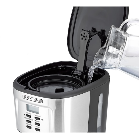 A close-up image of a BLACK+DECKER coffee maker with its lid open. Water is being poured from a glass container into the reservoir of the coffee machine.