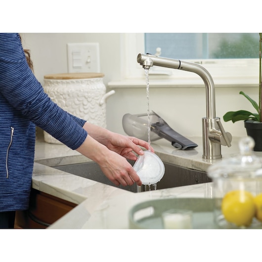 BLACKDECKER DVA320J handheld vacuum filter being rinsed under a kitchen faucet.