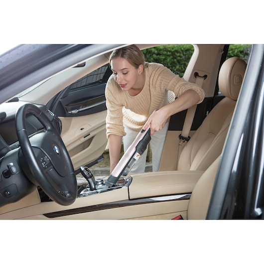 BLACKDECKER DVC320BRG handheld vacuum cleaner used for cleaning car interior, beige upholstery.