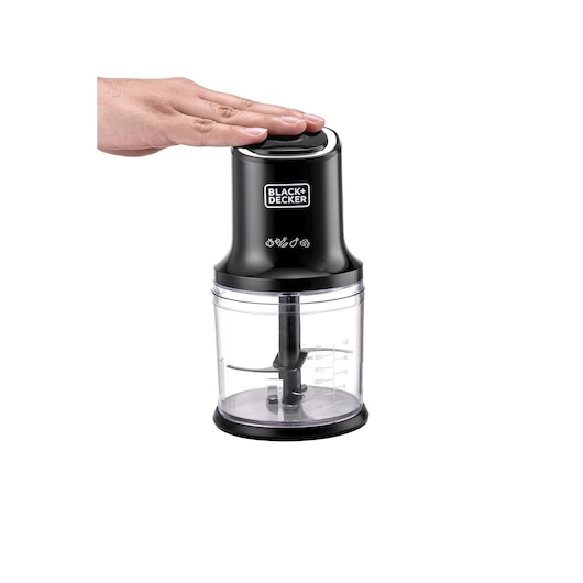 Photo of BLACK+DECKER FC500 food chopper with a hand pressing the black lid, clear measurement bowl visible, front angle.