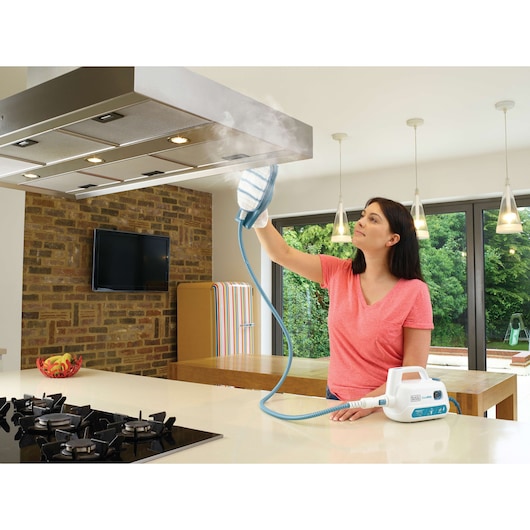 BLACKDECKER FSH10SM steam cleaner used on kitchen range hood by person in bright modern kitchen.