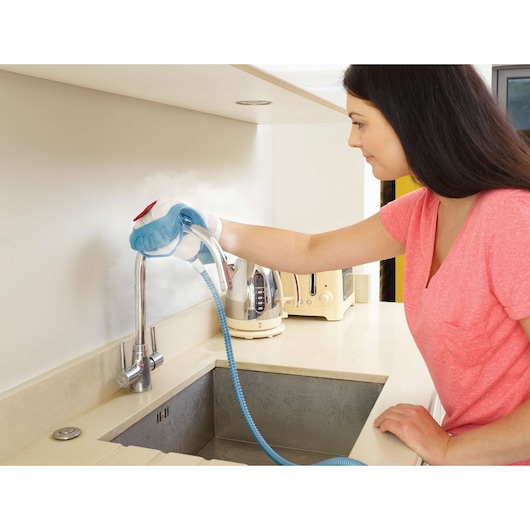 BLACKDECKER FSH10SM steam cleaner used on kitchen faucet, person wearing glove, countertop appliances.