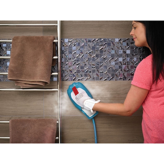Photo of BLACKDECKER FSH10SM steam cleaning glove used on tile wall in bathroom next to towel rack.