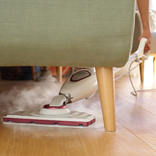 BLACKDECKER FSM1605R steam mop cleaning hardwood floor under green sofa.
