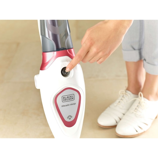 Photo of BLACK+DECKER FSM1605R steam mop being switched on, close-up of red and white body and control button.