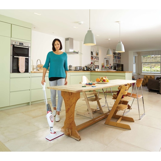 BLACKDECKER FSM1605R steam mop in use on kitchen tile floor, with wooden dining table and chairs.