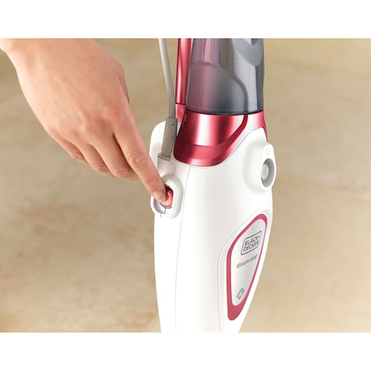 BLACKDECKER FSM1605R steam mop with red and white body, close-up of hand pressing power button.