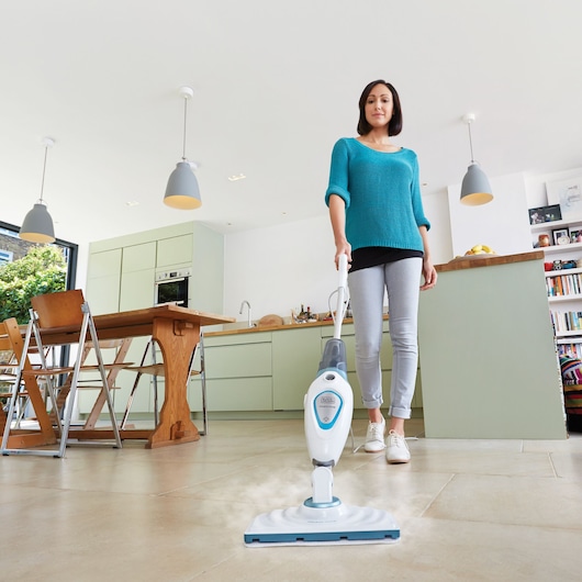 BLACKDECKER FSM1605 steam mop in use on kitchen floor, photography showing product cleaning action.