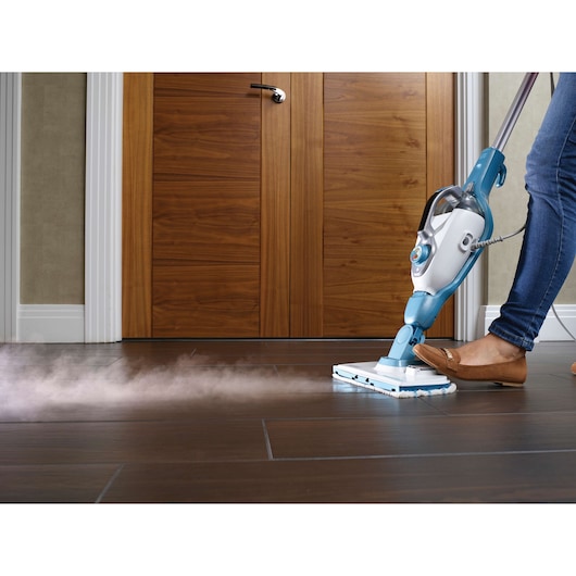 BLACKDECKER FSMH13151SM steam mop cleaning dark wood floor, person using product, front angle.