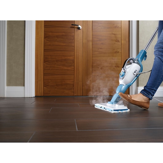 BLACKDECKER FSMH13151SM steam mop cleaning dark tile floor in front of wooden door.