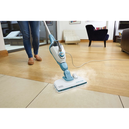 BLACKDECKER FSMH13151SM steam mop cleaning tile and wood floor in a modern living room, side angle