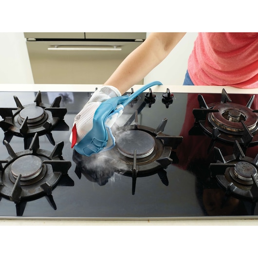 BLACKDECKER FSMH13151SM steam glove cleaning gas stove top, home kitchen, close-up angle.