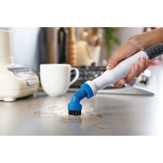 BLACK+DECKER FSMH13151SM steam cleaner brush nozzle cleaning kitchen countertop with stains, handheld view.