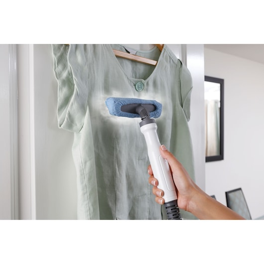 BLACKDECKER FSMH13151SM handheld steam cleaner used on light green shirt, front angle.