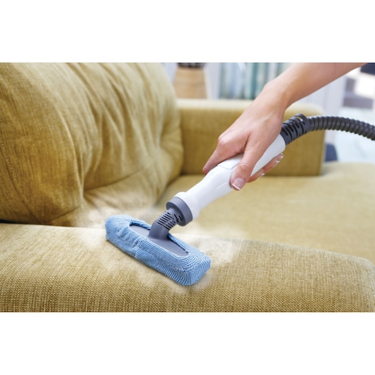 BLACKDECKER FSMH13151SM steam cleaner with blue microfiber pad cleaning yellow fabric sofa.