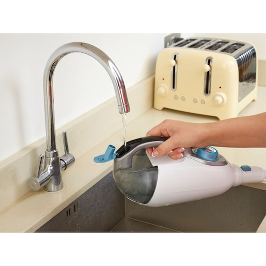 BLACKDECKER FSMH13151SM steam mop water tank being filled at kitchen sink, close-up side angle.