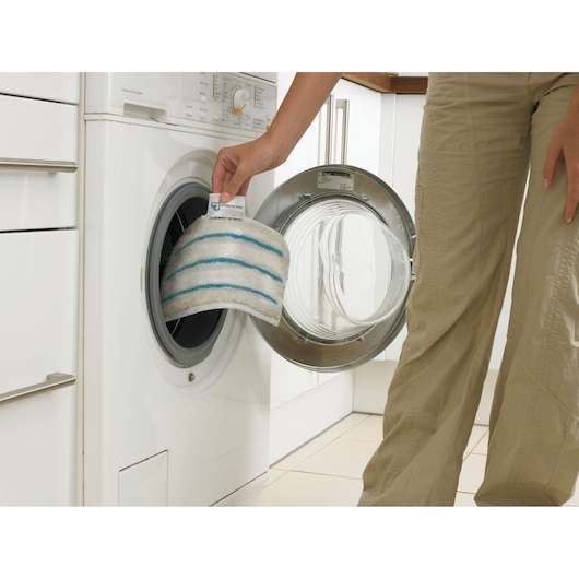 BLACKDECKER FSMP20 mop pad with blue stripes being placed in washing machine, side view, cleaning accessory.
