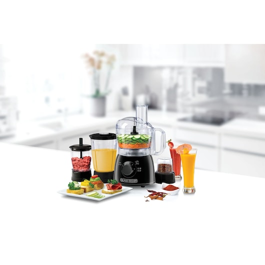 Photo of BLACK+DECKER FX400BMG food processor with attachments and assorted food, kitchen background.
