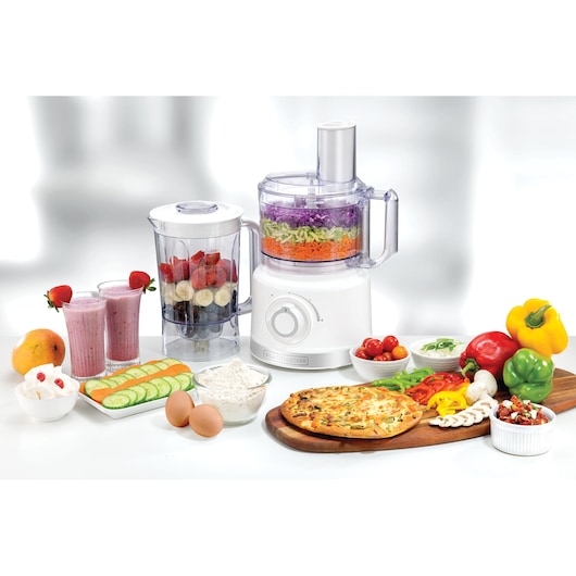 BLACK+DECKER FX760 food processor and blender with fruits, vegetables, pizza, and ingredients on table, front angle.