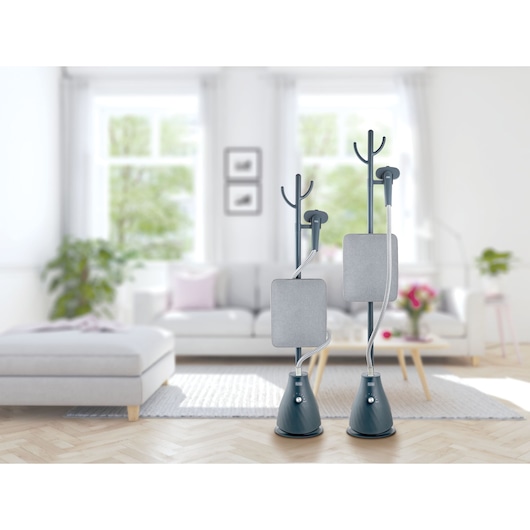 Photo of two BLACKDECKER GST1820 garment steamers with grey boards and black bases, displayed in a modern living room.