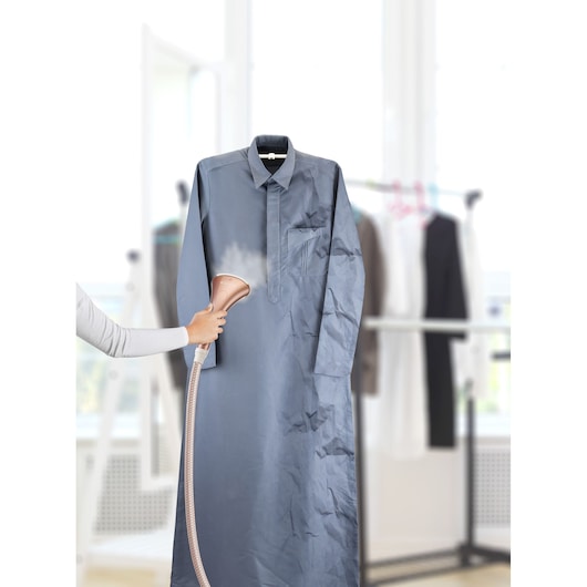 BLACKDECKER GSTD2050 garment steamer used on a wrinkled shirt, indoor setting.