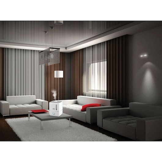 BLACKDECKER HM3000 white humidifier on coffee table in modern living room with sofas and red cushions.