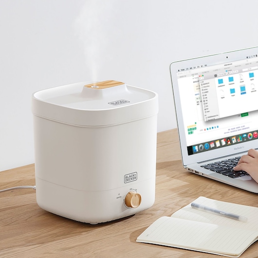 BLACK+DECKER HM4125 humidifier with wooden knob and top accent on table beside laptop and notebook.