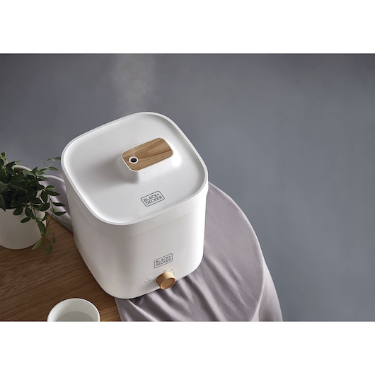 Photo of BLACKDECKER HM4125 white humidifier with wood accent, placed on table with cup and plant visible.