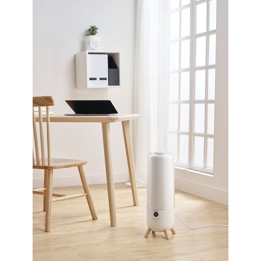 BLACKDECKER HM6000 air purifier with cylindrical white body and wooden legs, placed in a modern home office.