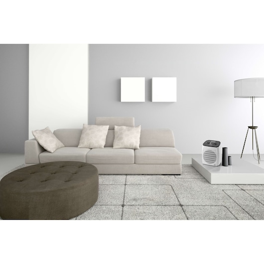 BLACKDECKER HX310 heater placed on modern white table in minimalist living room with beige sofa and floor lamp.