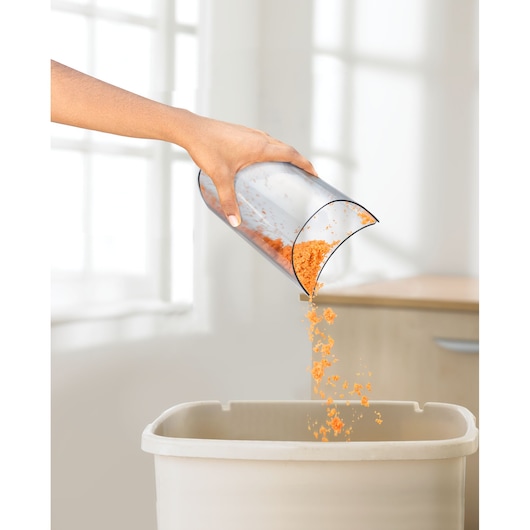 BLACKDECKER JE250 juicer pulp container being emptied over a bin in a kitchen setting.