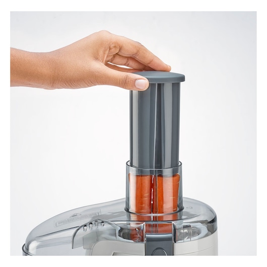 BLACKDECKER JE250 juicer close-up with a hand pressing down plunger on carrots, front angle, white background.