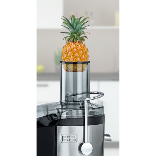 BLACKDECKER JE800 juicer with a whole pineapple in feeding tube, stainless steel front, kitchen background