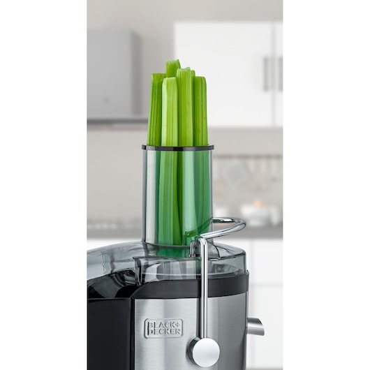 BLACK+DECKER JE800 juicer with celery stalks in the feed chute, close-up kitchen view.